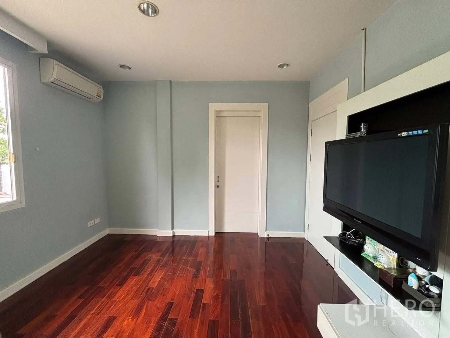 Detached House for rent in Bang Kapi, Bangkok - Secondary bedroom with wall-mounted TV and wood floors.