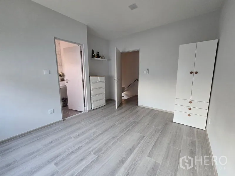 Detached House for rent in Bang Phli, Samut Prakan - Empty upstairs room with wardrobe, door to ensuite bathroom and grey wood flooring.