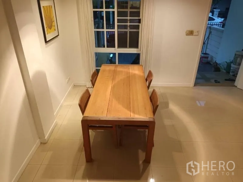 Townhouse for rent in Bang Kapi, Bangkok - Dining room with a solid wood table for four placed beside a large window.