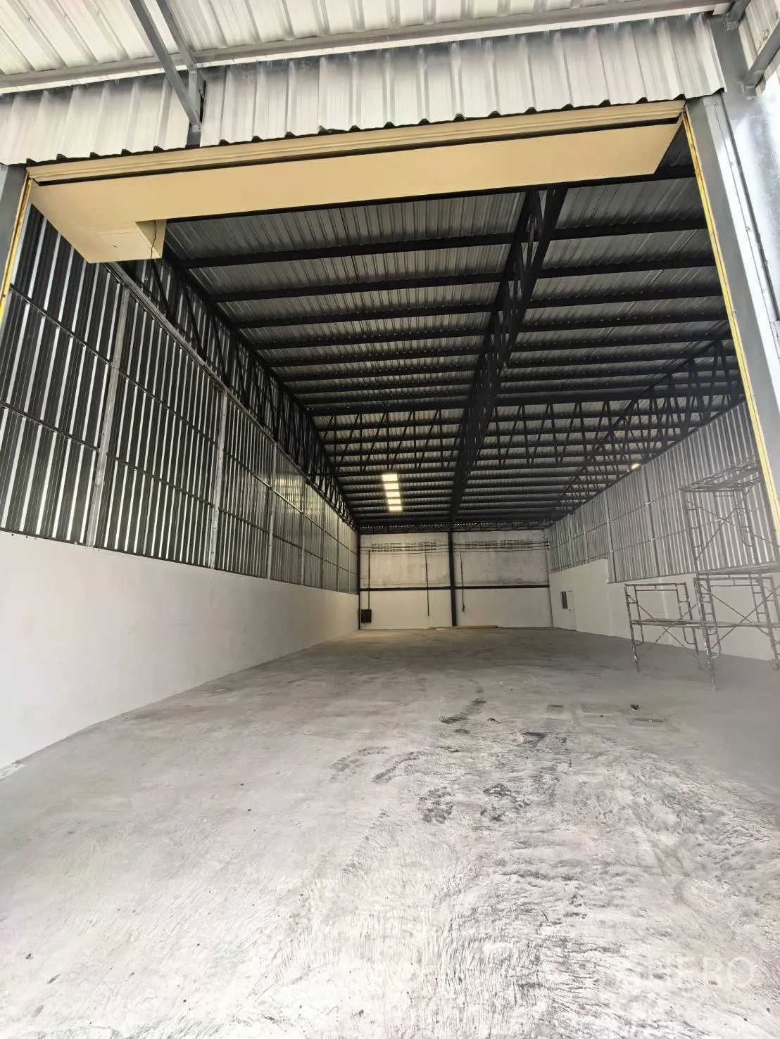 Warehouse for rent in Suan Luang, Bangkok - View from the entrance into a long open warehouse with concrete floor and high steel truss roof.