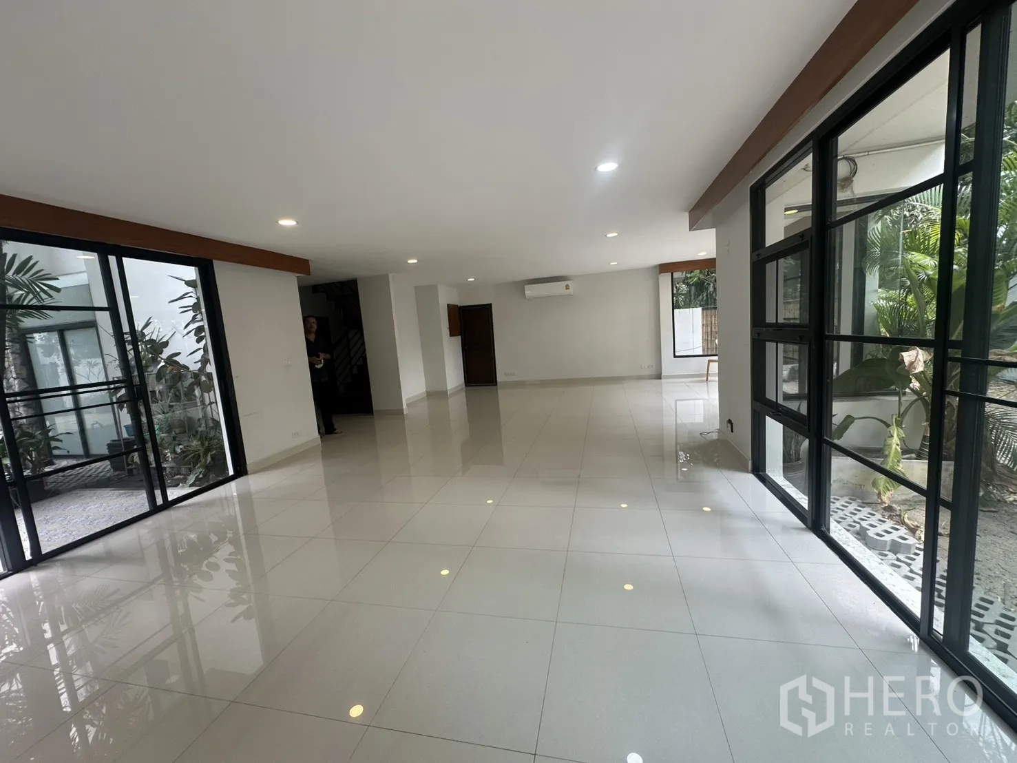 Detached House for rent in Watthana, Bangkok - Open living area with sliding glass doors to a courtyard and floor-to-ceiling windows.