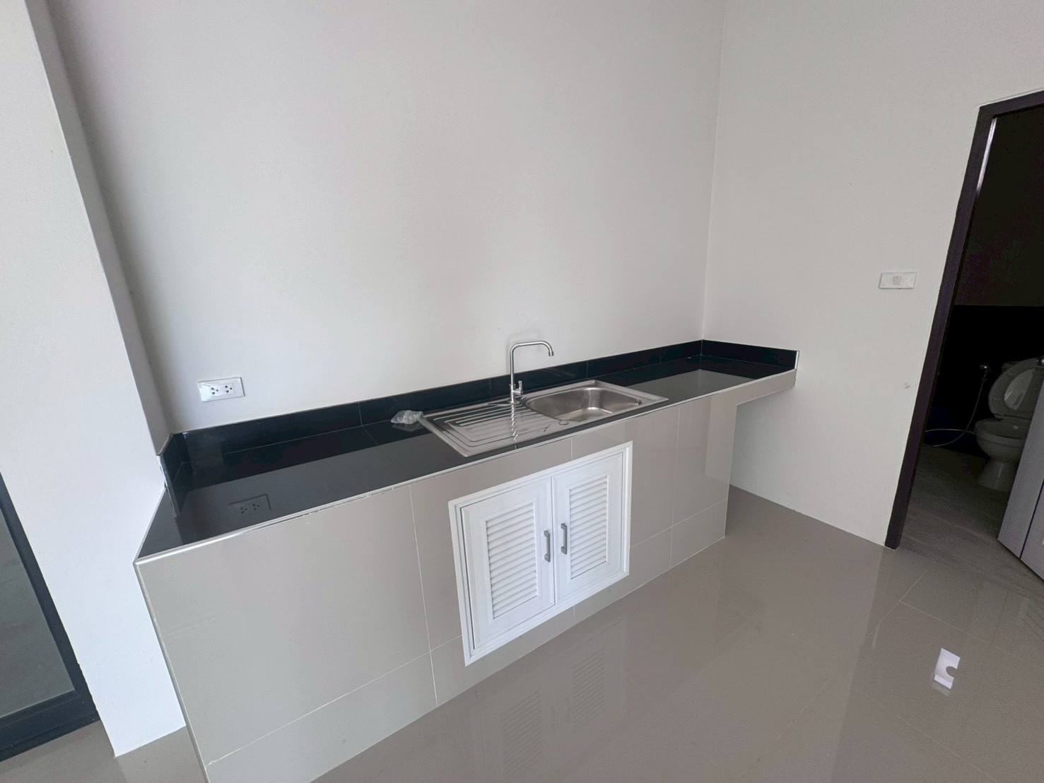 Factory for sale in Mueang Samut Sakhon, Samut Sakhon - Built-in pantry with black countertop, stainless sink and tiled finish.