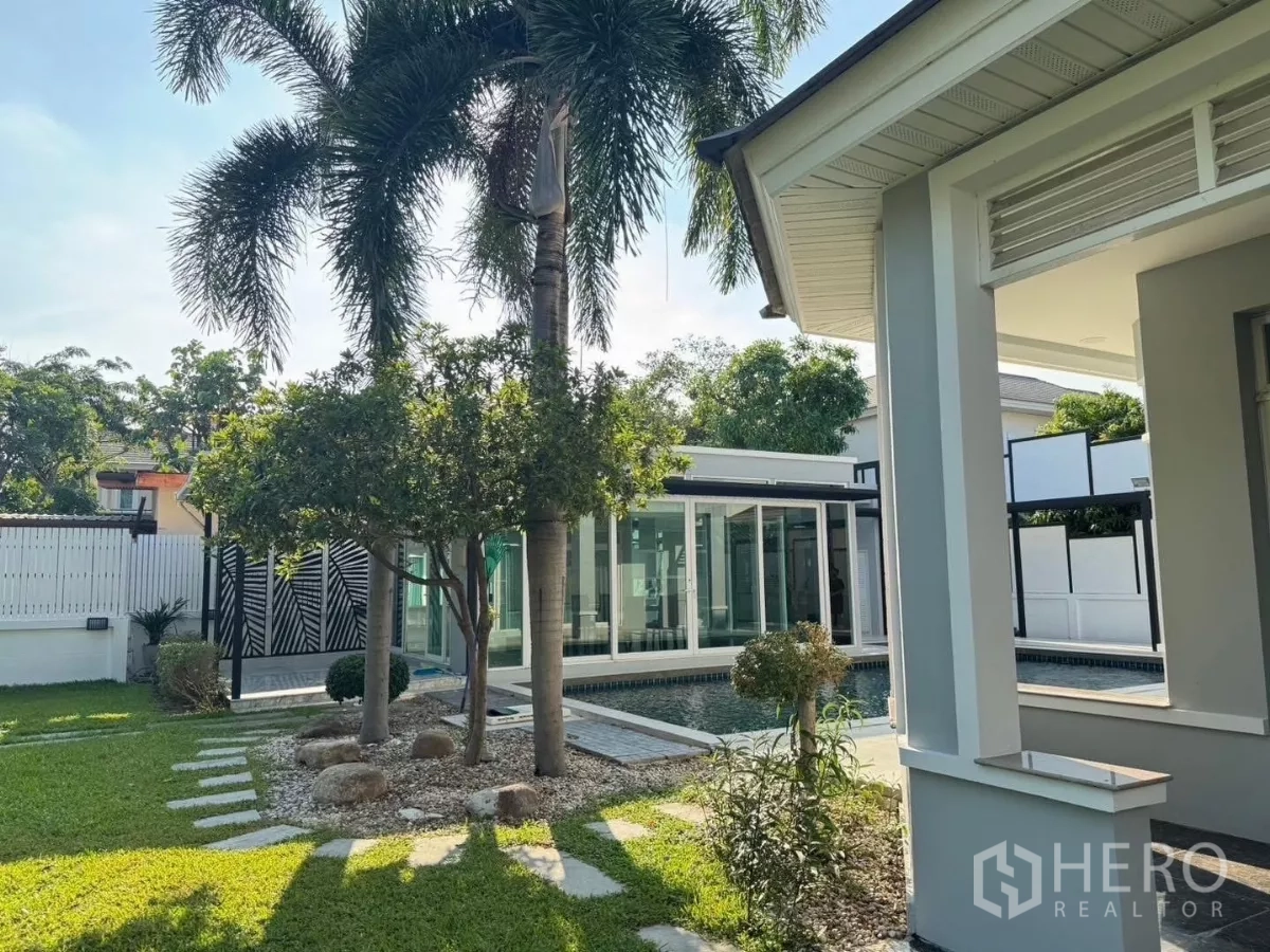 Detached House for rent or sale in Prawet, Bangkok - Landscaped garden with palm trees, stepping-stone path and a private pool-style water feature.
