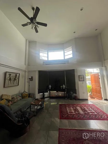 Home Office for rent in Bang Rak, Bangkok - High-ceiling living room with bay window and wooden front door opening to the patio.