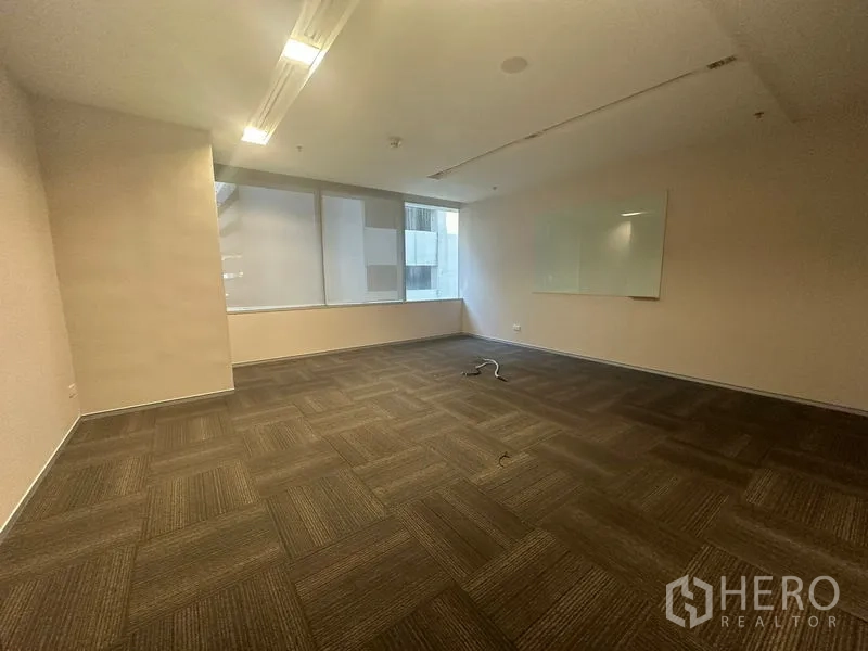Office Space for rent in Khlong Toei, Bangkok - Enclosed office with carpet tiles, a window, and a wall-mounted whiteboard.