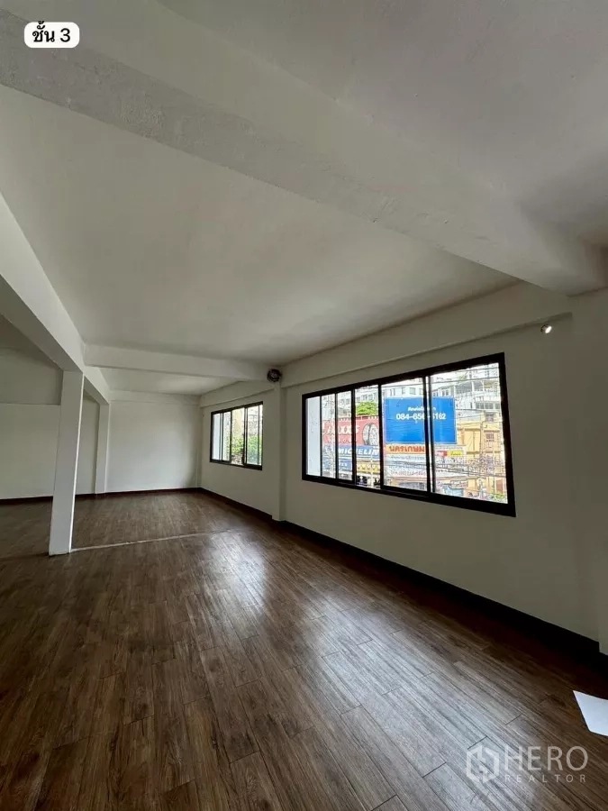 Shophouse for rent or sale in Khlong Toei, Bangkok - Bright third-floor open-plan room with large windows and wood-look flooring.