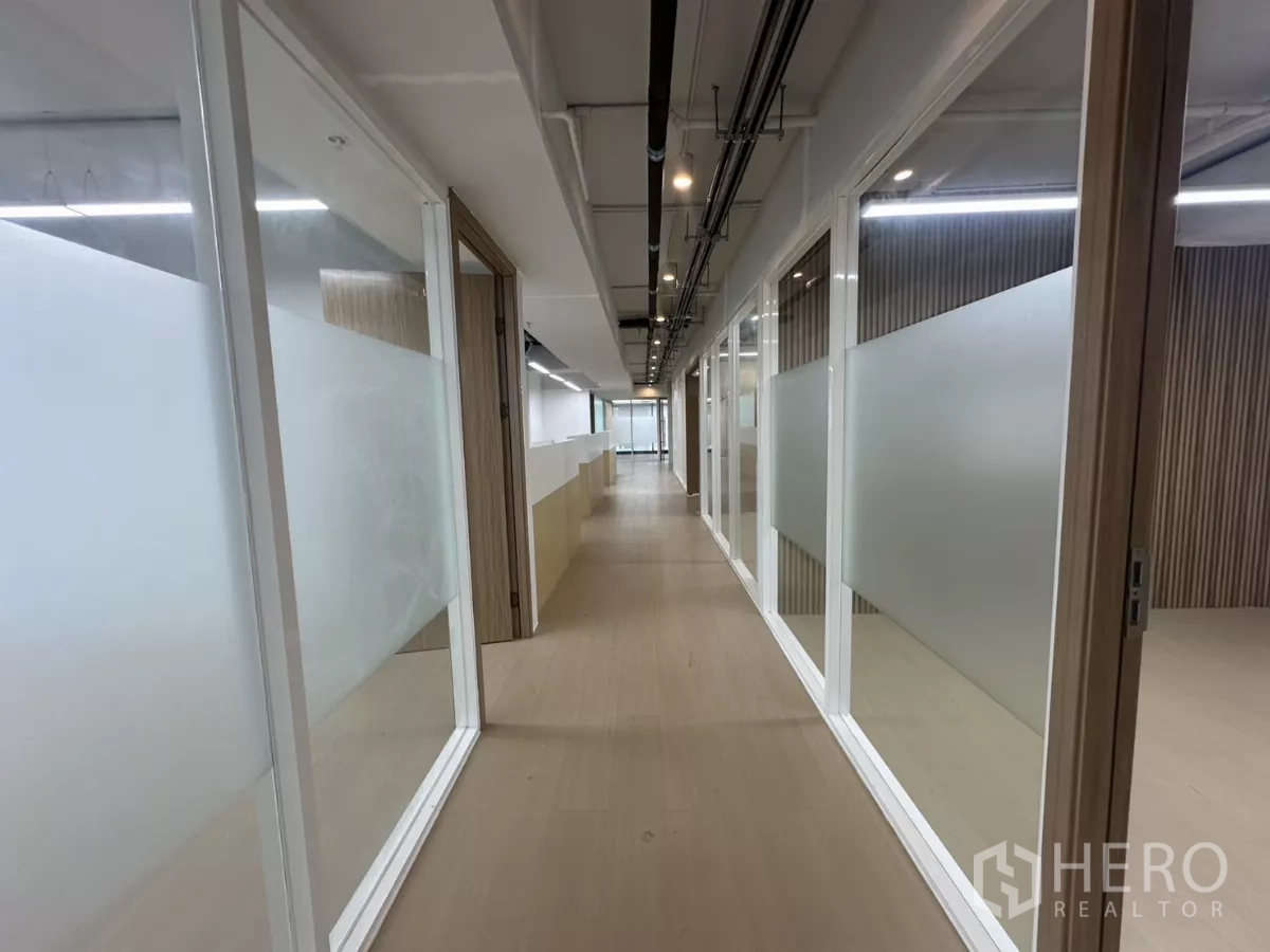 Office Space for rent in Watthana, Bangkok - Corridor lined with glass-partitioned offices and LED lighting.
