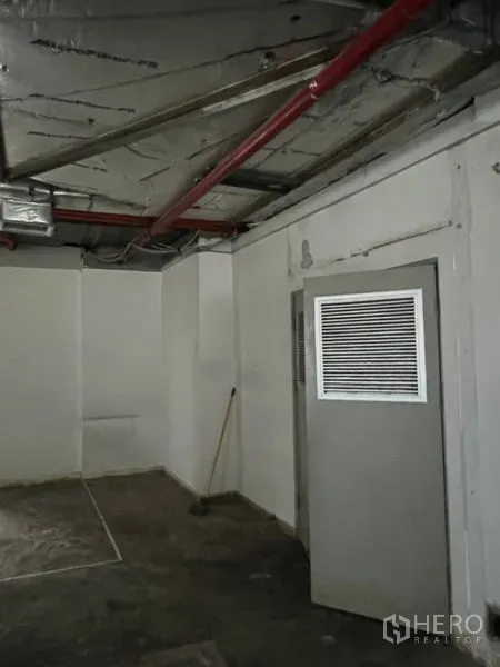 Office Space for rent - Utility room door with ventilation grille beneath exposed piping and ductwork inside the office.