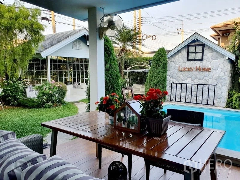 Detached House for sale in Lam Luk Ka, Pathum Thani - Covered terrace with wooden dining set overlooking landscaped garden and private pool with pavilion.