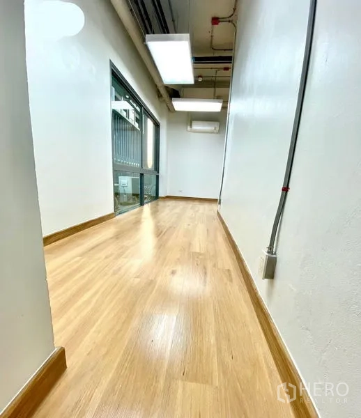 Office Space for rent in Khlong Toei, Bangkok - Corridor‑style workspace with wood flooring, side window and exposed ceiling services.