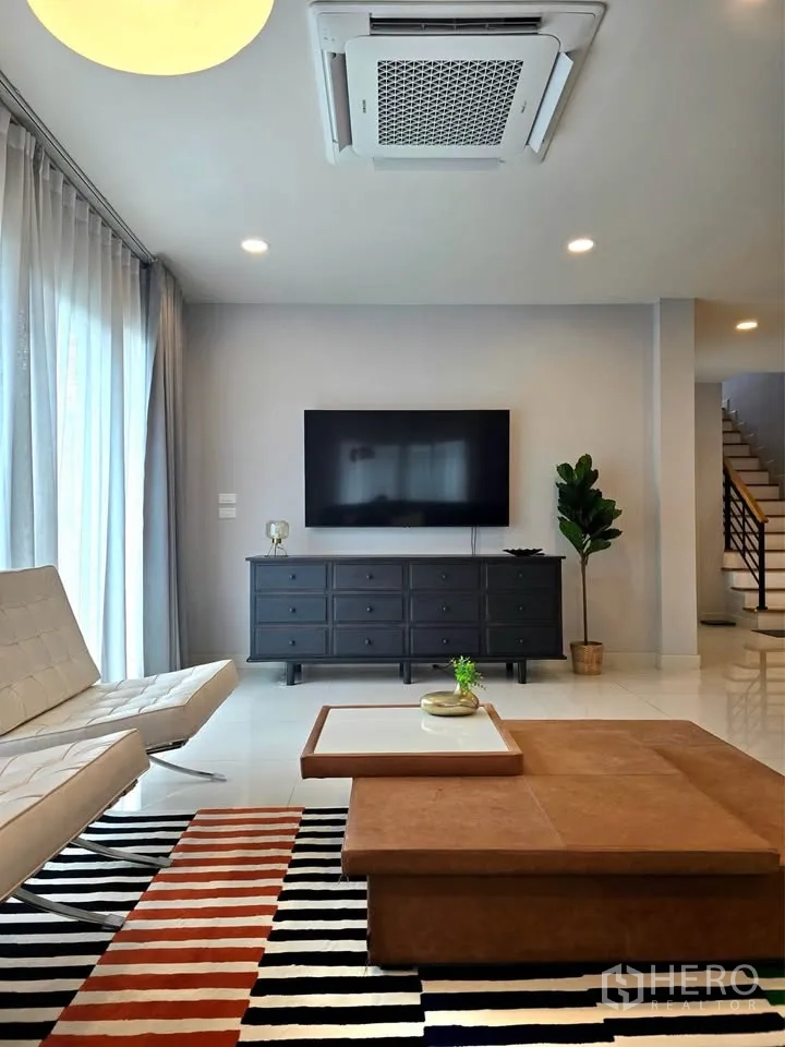 独栋房屋 for rent or sale in Bang Phli, Samut Prakan - 客厅配挂墙电视、矮柜与天花嵌入式空调机。