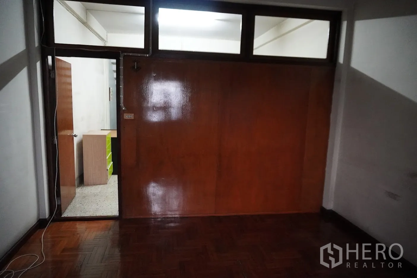 店屋 出租在Watthana, Bangkok - 房间带亮光木质墙面与人字拼地板，通向小走道。