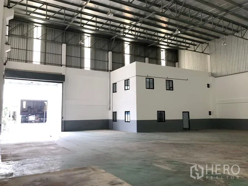 Factory for rent or sale in Samut Prakan - Spacious production area with high ceiling and corner office structure inside the factory.