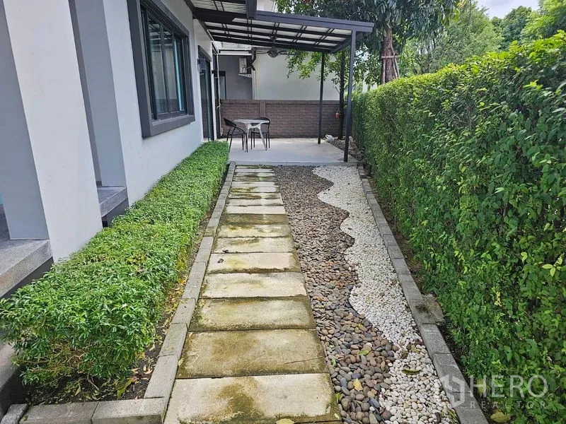 Detached House for rent or sale in Lam Luk Ka, Pathum Thani - Side garden with stepping-stone path, pebble landscaping and a covered patio
