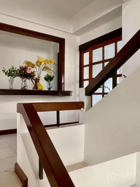 Home Office for rent in Khlong Toei, Bangkok - Bright stairwell with wooden handrails and glass door, decorative shelf with flowers.