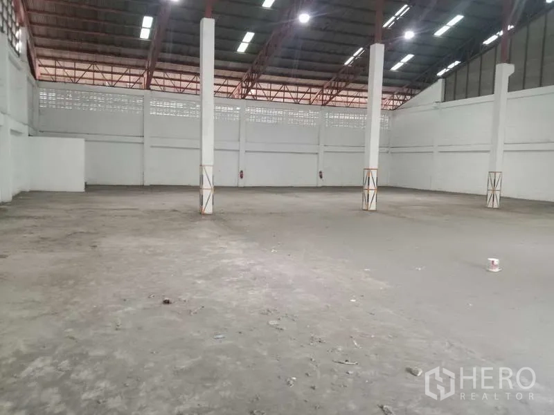 Factory for rent in Samut Prakan - Spacious warehouse interior with columns and durable concrete floor.