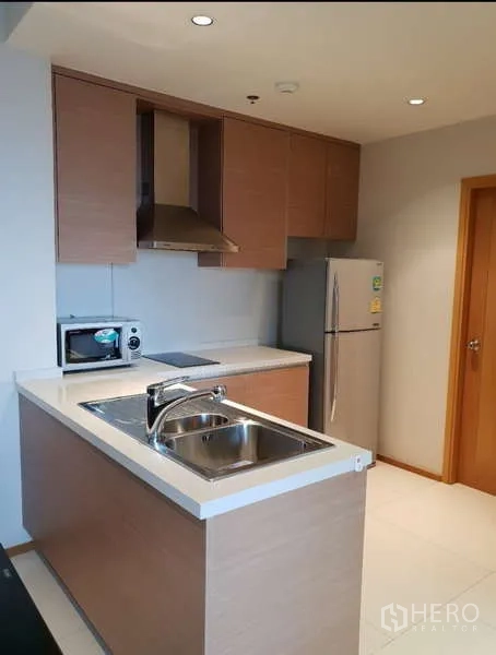 Condominium for rent - Compact modern kitchen with island sink, cooktop, range hood, microwave and refrigerator.
