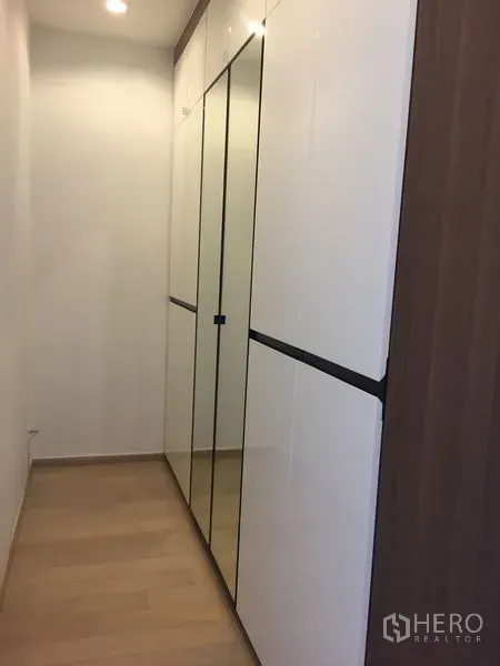 Condominium for rent in Watthana, Bangkok - Built-in mirrored wardrobe in a bright hallway with light wood flooring.