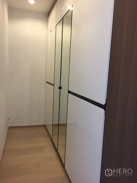 Condominium for rent in Watthana, Bangkok - Built-in mirrored wardrobe in a bright hallway with light wood flooring.