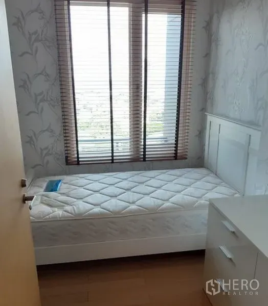 Condominium for rent in Khlong Toei, Bangkok - Cozy secondary bedroom with single bed, dresser, and large window with blinds.