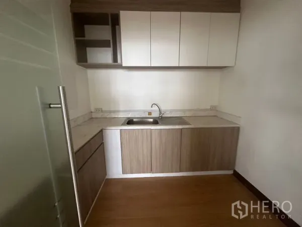 Office Space for rent in Bang Rak, Bangkok - Compact office pantry with upper and lower cabinets, sink and stone-look countertop.