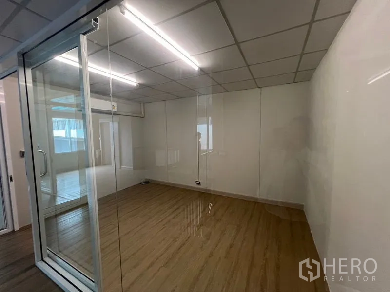 Warehouse for rent in Prawet, Bangkok - Enclosed glass office room with sliding door and fluorescent lighting.