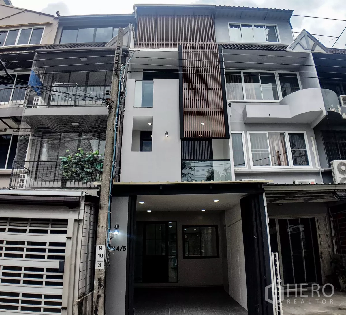 Townhouse for sale in Watthana, Bangkok - Modern four-storey townhouse exterior with vertical wood slats and a covered carport in the Sukhumvit area.