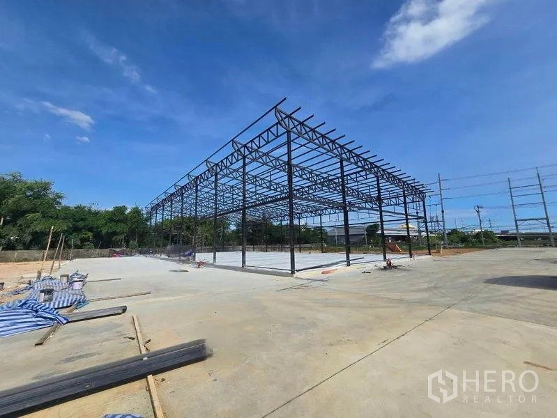 Warehouse for rent in Bang Phli, Samut Prakan - Wide-angle view of steel truss warehouse frame with spacious yard for maneuvering.
