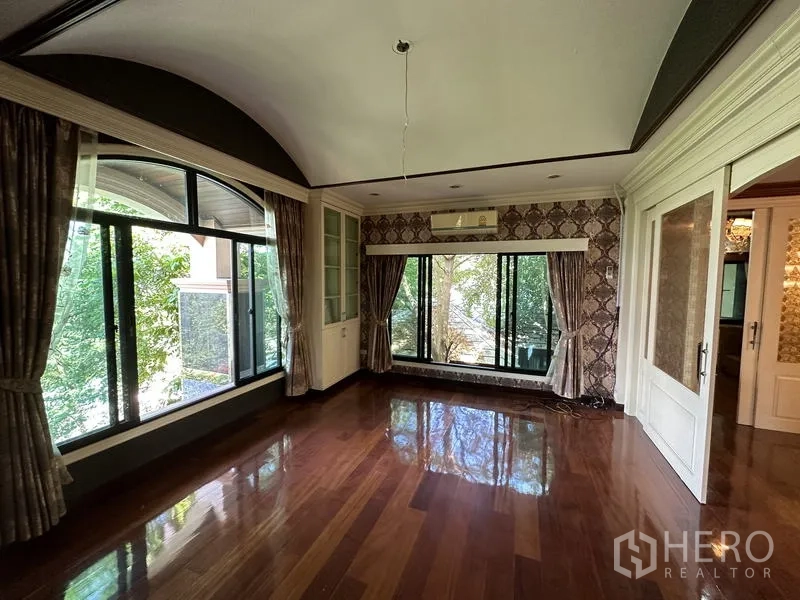 Detached House for sale in Lam Luk Ka, Pathum Thani - Sunlit bedroom with large arched window and wood flooring