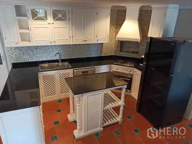 Detached House for rent in Mueang Samut Prakan, Samut Prakan - Overhead view of the kitchen showing island, extractor hood, black counters and tiled floor.