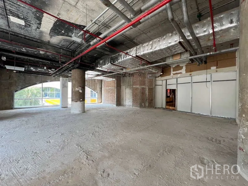 Retail Space for rent - Open-plan corner retail unit with central columns, metallic insulated ceiling and floor-to-ceiling arched glazing.