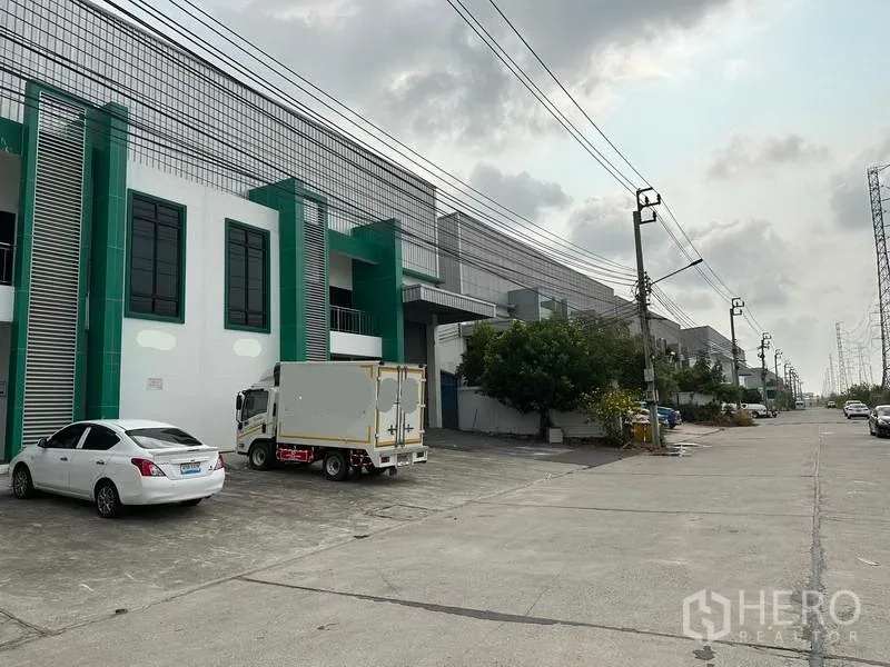 Factory for rent or sale in Bang Phli, Samut Prakan - Street view of industrial row in Bang Phli with factories, parking and power lines.