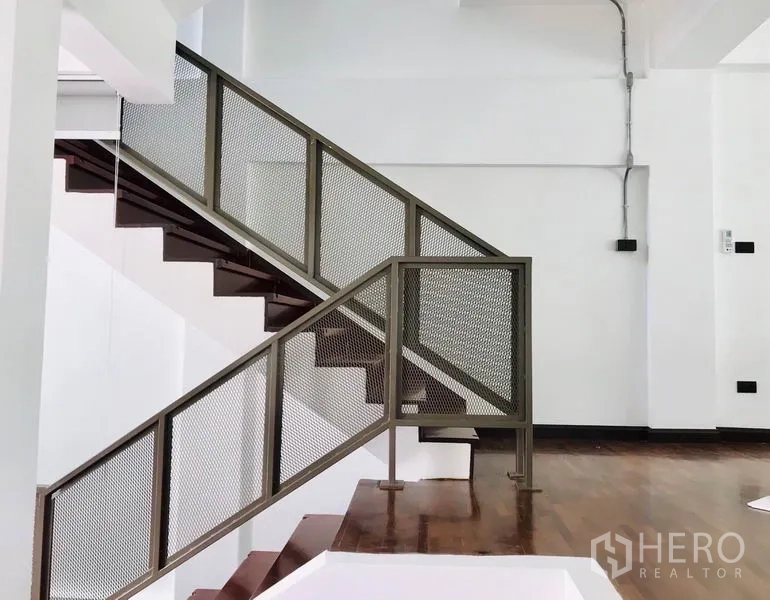 Townhouse for rent or sale in Khlong Toei, Bangkok - Open staircase with metal mesh railing and wooden treads.