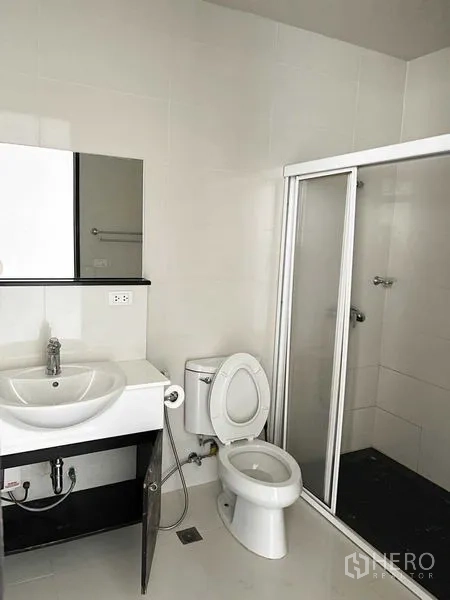 Condominium for rent in Pathum Wan, Bangkok - Modern bathroom with white vanity, toilet and glass-enclosed walk-in shower.