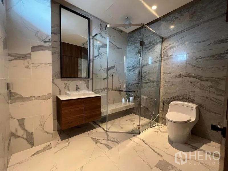 Detached House for sale in Suan Luang, Bangkok - Bathroom with marble-look tiles, glass shower enclosure and vanity.