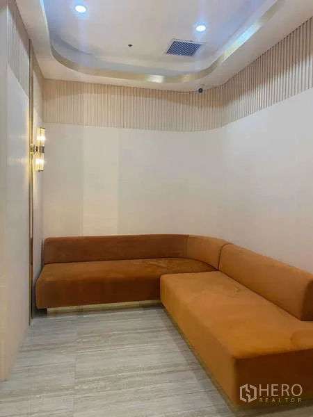 Office Space for rent in Huai Khwang, Bangkok - Cozy breakout room with L-shaped orange sofa, wood-accent walls and tiled floor.