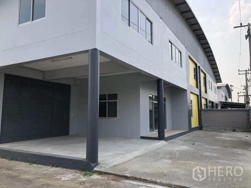 Factory for rent in Lat Lum Kaeo, Pathum Thani - Covered loading bay with roller shutter door and reinforced columns at the front of the factory.