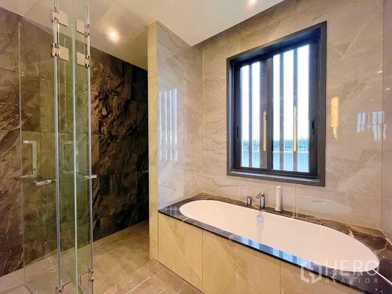 Detached House for sale in Bang Phli, Samut Prakan - Bathroom featuring a soaking bathtub beneath a window and a separate glass shower with marble finishes.