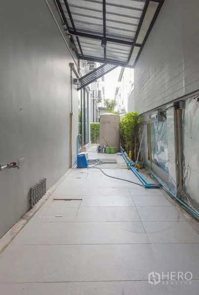 Detached House for rent or sale in Lat Phrao, Bangkok - Covered side utility area with tiled floor, water tank and washing points.