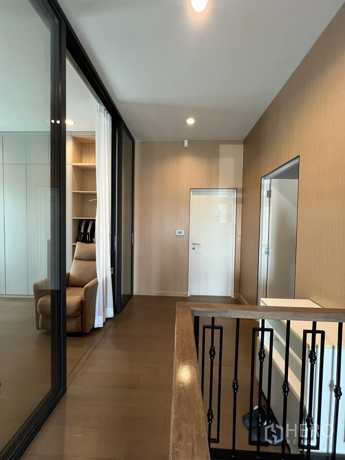 Detached House for rent or sale in Mueang Pathum Thani, Pathum Thani - Upper hallway with black iron balustrade and glass-enclosed room.