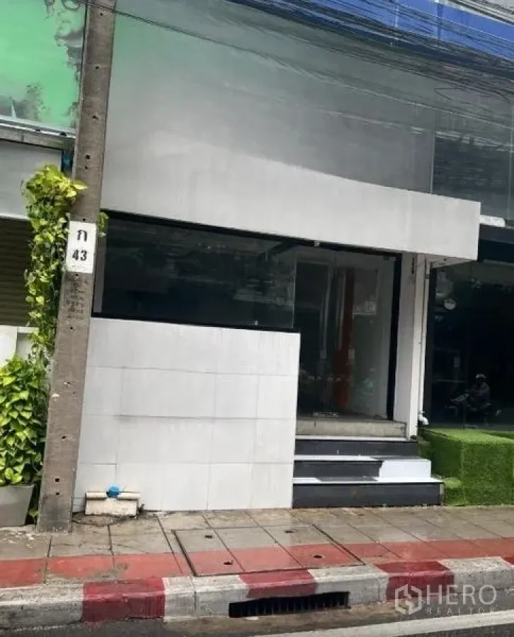 Retail Space for rent in Watthana, Bangkok - Compact storefront featuring a modern white exterior, raised entrance steps and wide display glass facing the street.
