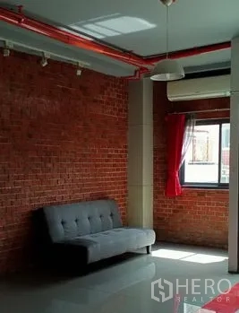 Office Space for rent in Khlong Toei, Bangkok - Seating nook against an exposed brick wall with track lights and an air-conditioner.