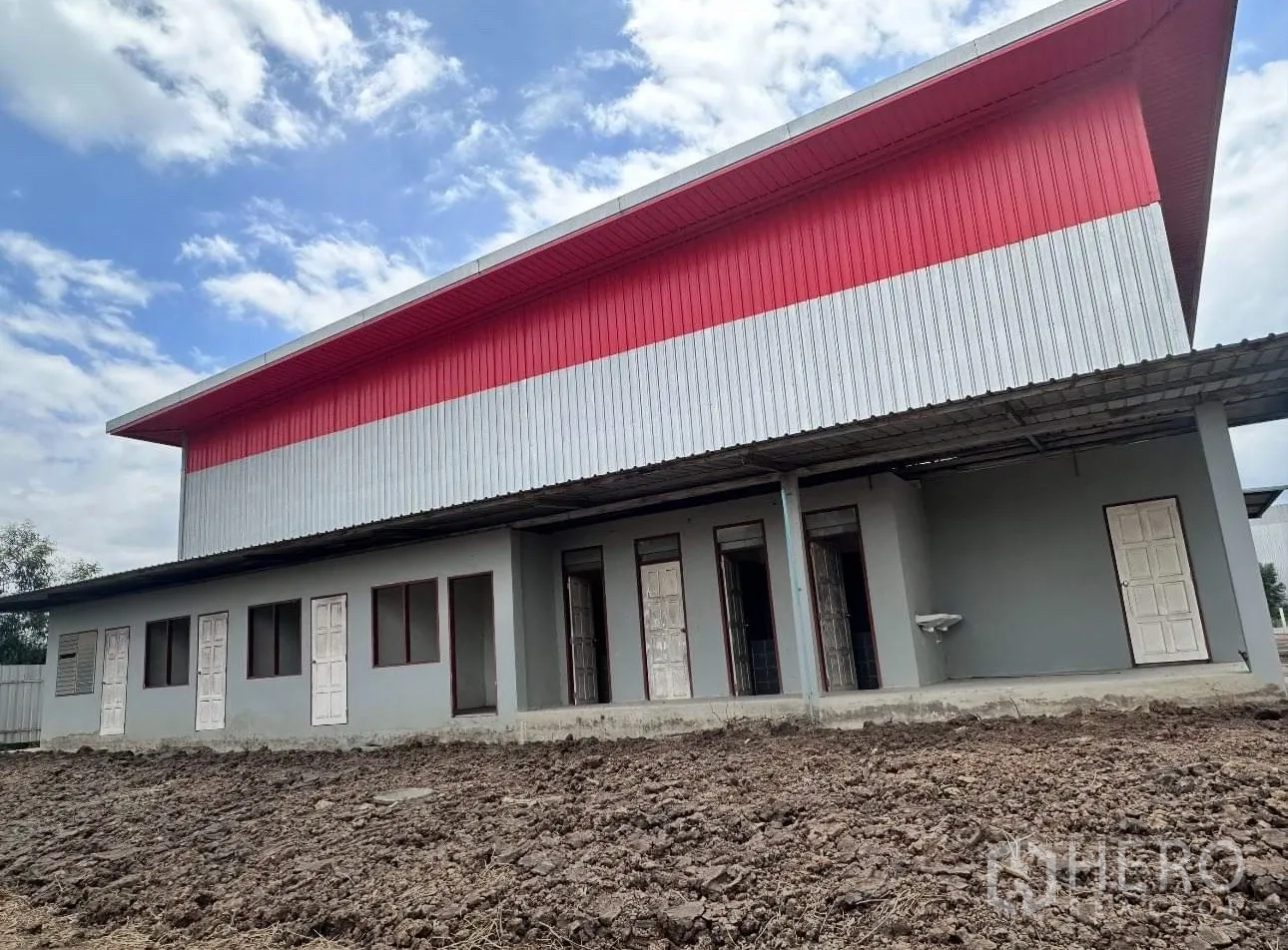 Warehouse for sale in Sai Noi, Nonthaburi - Rear facade of the warehouse featuring several access doors and a covered walkway.