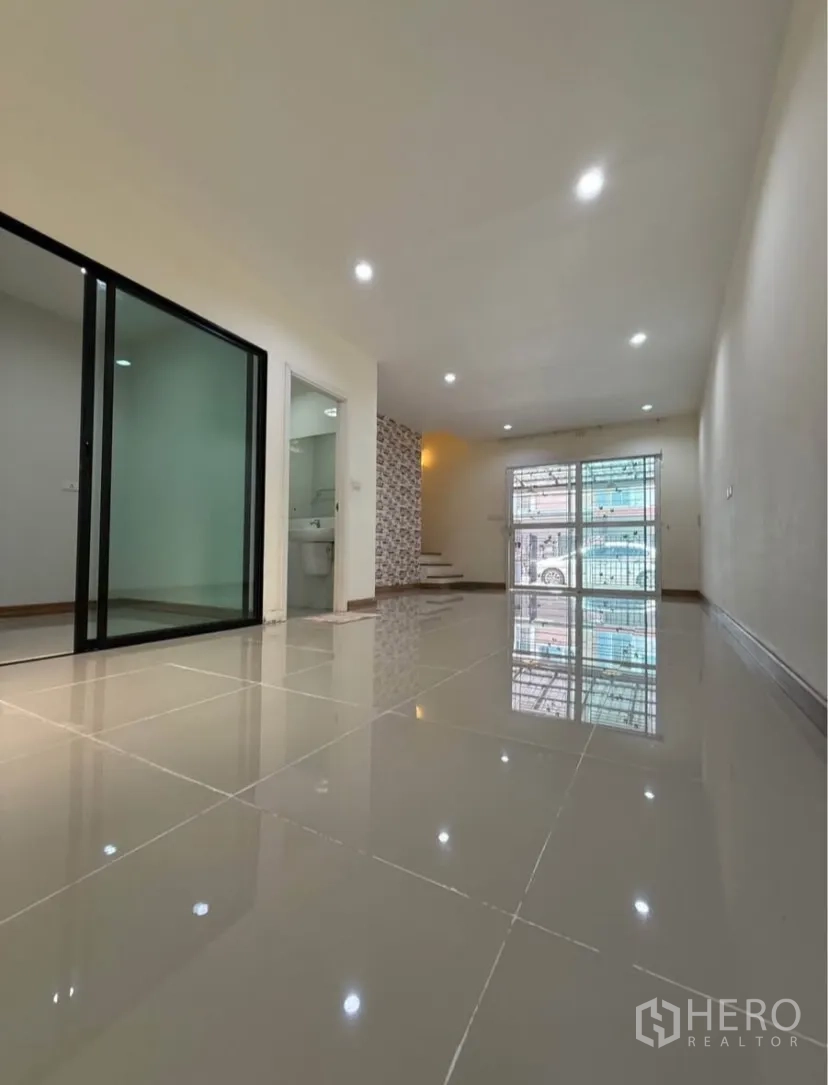 Townhouse for rent in Suan Luang, Bangkok - Bright ground-floor living area with glossy tiles and sliding glass door.
