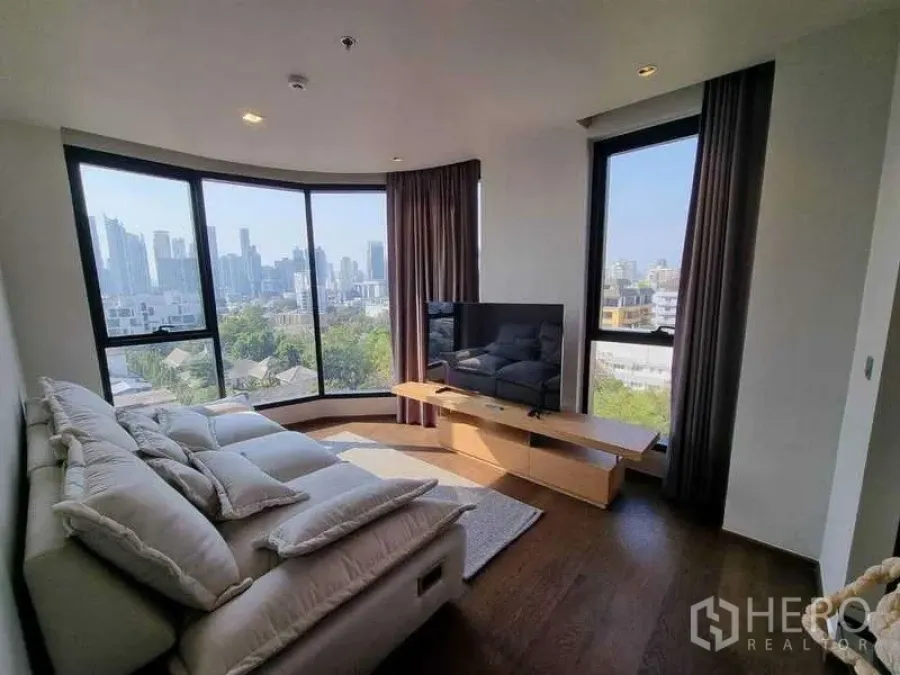 Condominium for rent in Khlong Toei, Bangkok - Panoramic living area with wraparound windows showcasing the Bangkok skyline.