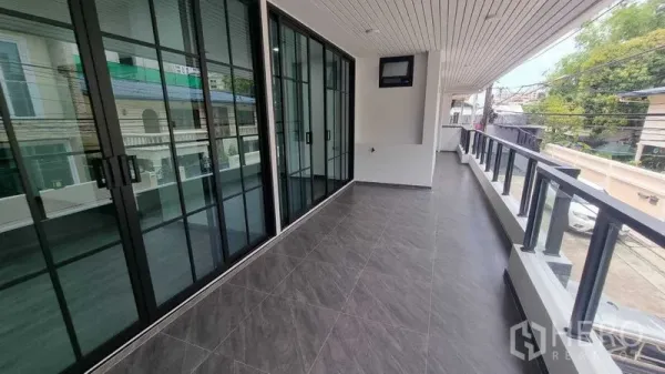 Townhouse for rent in Khlong Toei, Bangkok - Long covered balcony with glass railing and large sliding doors overlooking the street.