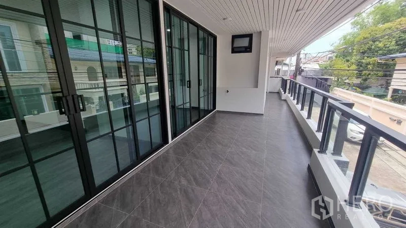 Townhouse for rent in Khlong Toei, Bangkok - Long covered balcony with glass railing and large sliding doors overlooking the street.