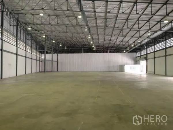 Warehouse for rent in Bang Phli, Samut Prakan - Spacious high-ceiling warehouse interior with concrete floor and bright lighting.