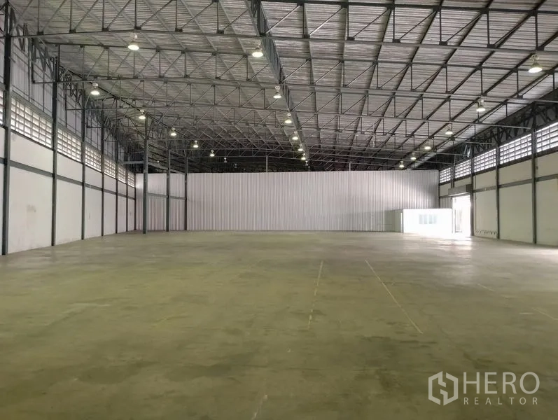 Warehouse for rent in Bang Phli, Samut Prakan - Spacious high-ceiling warehouse interior with concrete floor and bright lighting.
