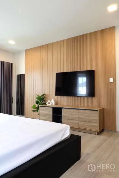 Detached House for rent in Bang Phli, Samut Prakan - Bedroom wall-mounted TV on vertical wood panel and low console.